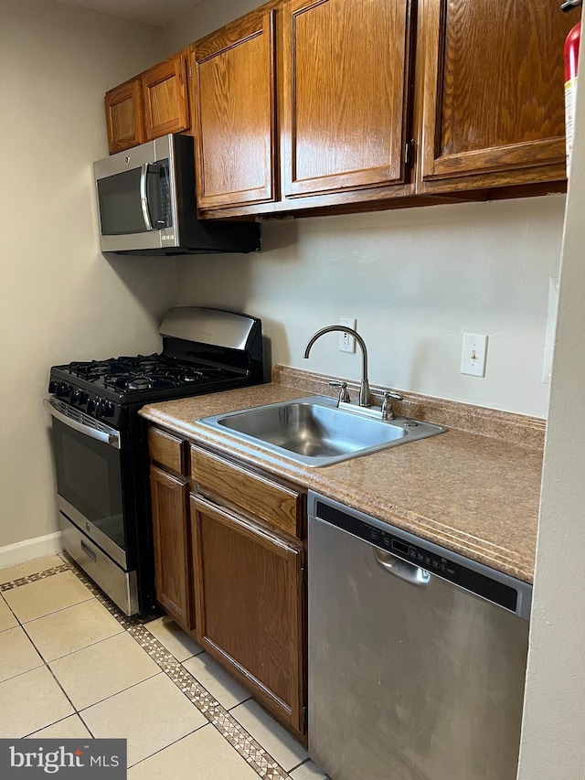 kitchen with light tile patterned floors, stainless steel appliances, and sink