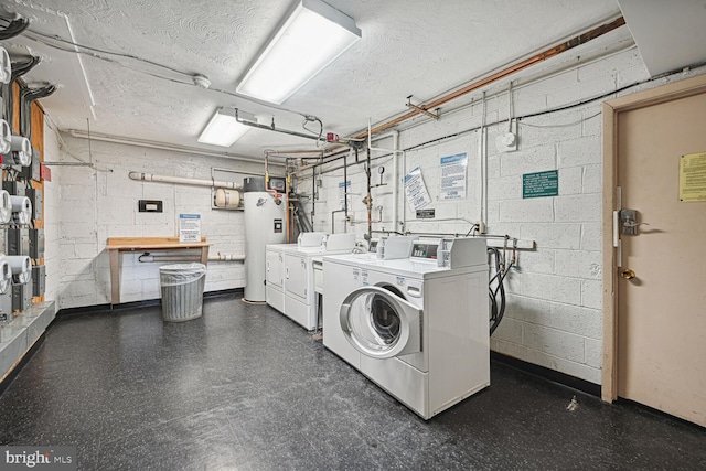 laundry room featuring a textured ceiling, water heater, a workshop area, and washer and dryer