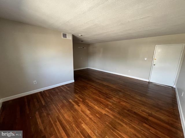 spare room with a textured ceiling and dark hardwood / wood-style flooring