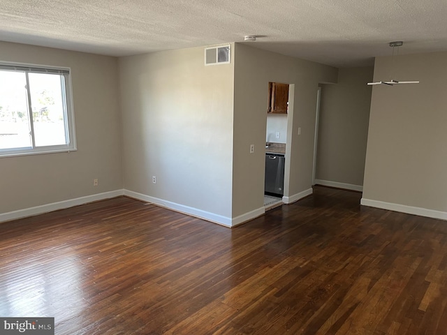 spare room featuring a textured ceiling and dark wood-type flooring