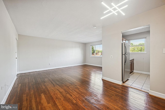 empty room featuring wood-type flooring, a textured ceiling, and a wealth of natural light