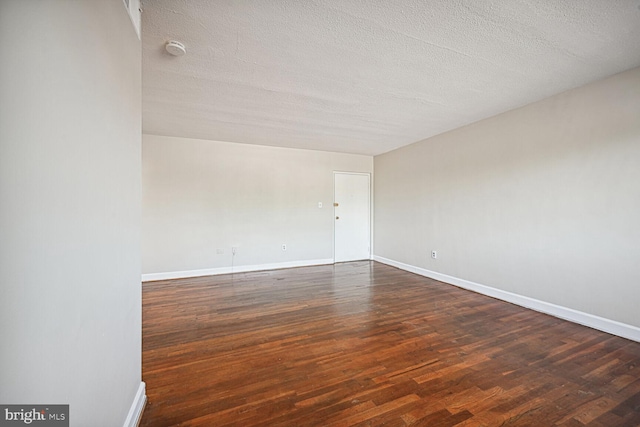 spare room with a textured ceiling and dark wood-type flooring