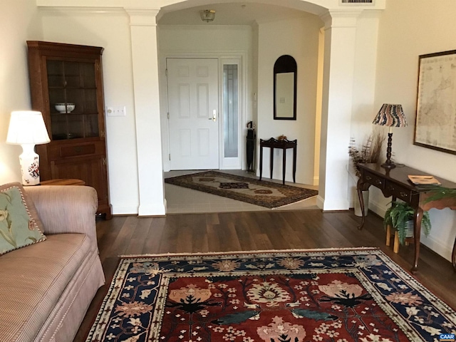 corridor featuring decorative columns, dark hardwood / wood-style flooring, and ornamental molding