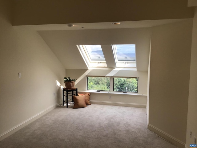 additional living space featuring lofted ceiling with skylight and light colored carpet