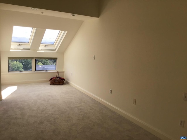 additional living space with lofted ceiling with skylight and carpet floors