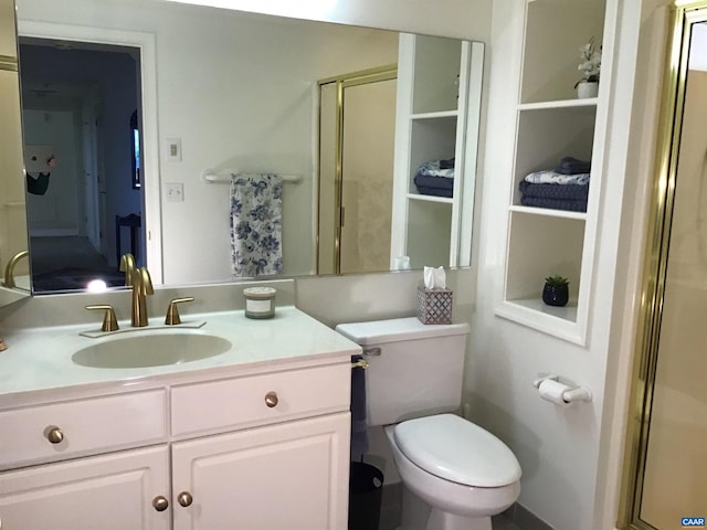 bathroom featuring toilet, vanity, and a shower with door