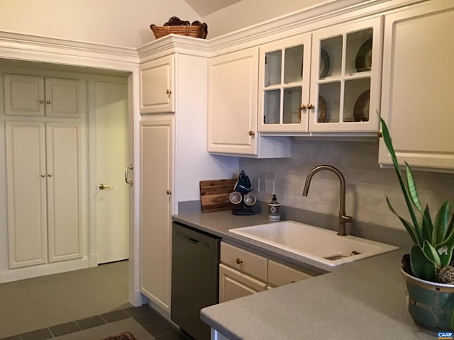 kitchen featuring decorative backsplash, white cabinetry, dark tile patterned floors, stainless steel dishwasher, and sink