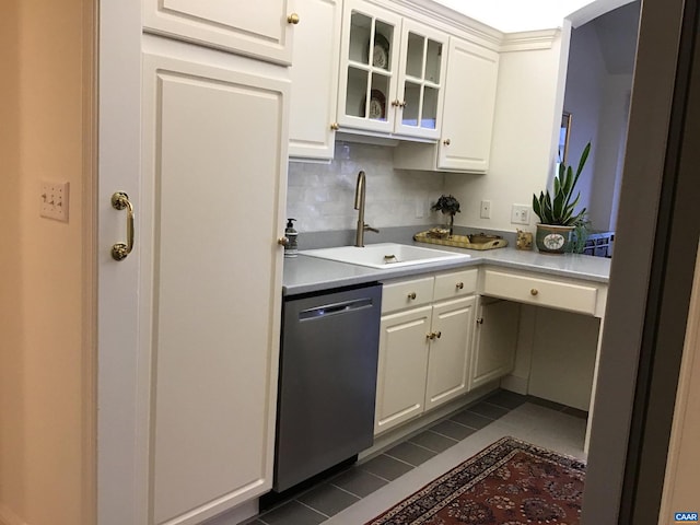 kitchen with white cabinets, backsplash, dark tile patterned floors, stainless steel dishwasher, and sink