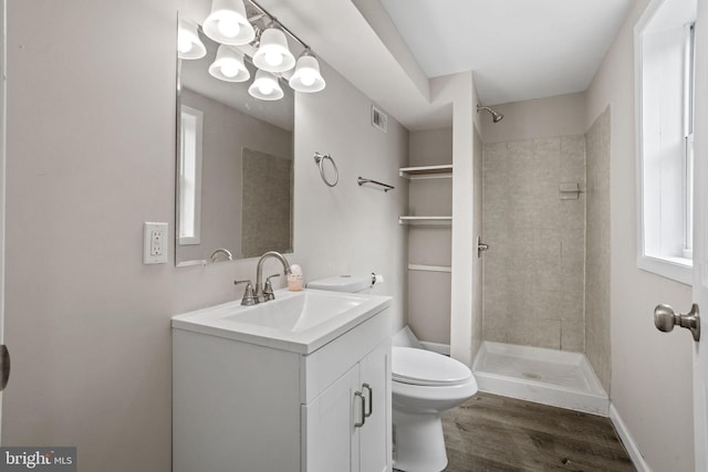 bathroom featuring vanity, hardwood / wood-style floors, toilet, and tiled shower