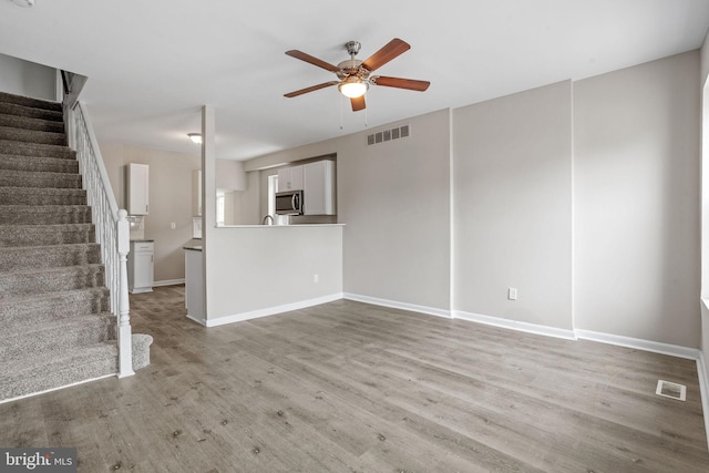 unfurnished living room with light hardwood / wood-style flooring and ceiling fan