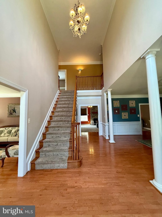 stairs featuring crown molding, hardwood / wood-style flooring, high vaulted ceiling, and a notable chandelier