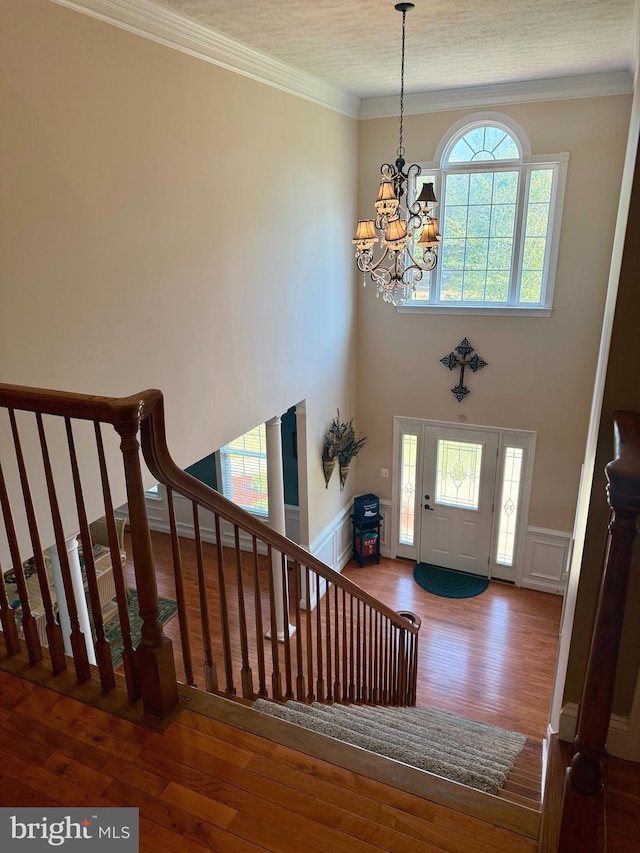 entryway featuring hardwood / wood-style flooring, ornamental molding, an inviting chandelier, and a textured ceiling