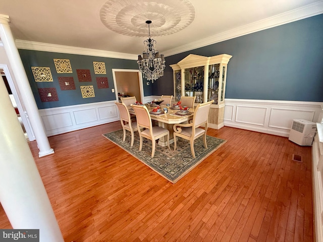 dining space featuring ornamental molding, hardwood / wood-style floors, a chandelier, and decorative columns