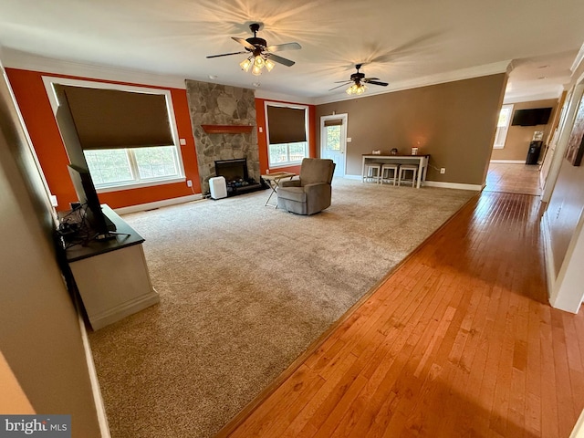 unfurnished living room featuring a wealth of natural light, a fireplace, hardwood / wood-style flooring, and ceiling fan