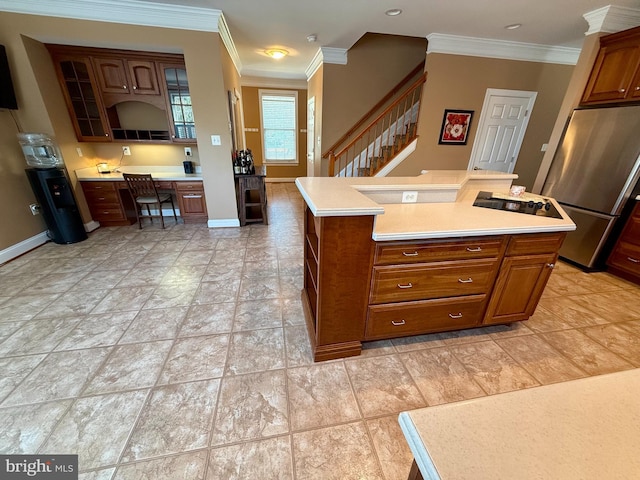 kitchen with built in desk, ornamental molding, a kitchen island, and stainless steel refrigerator