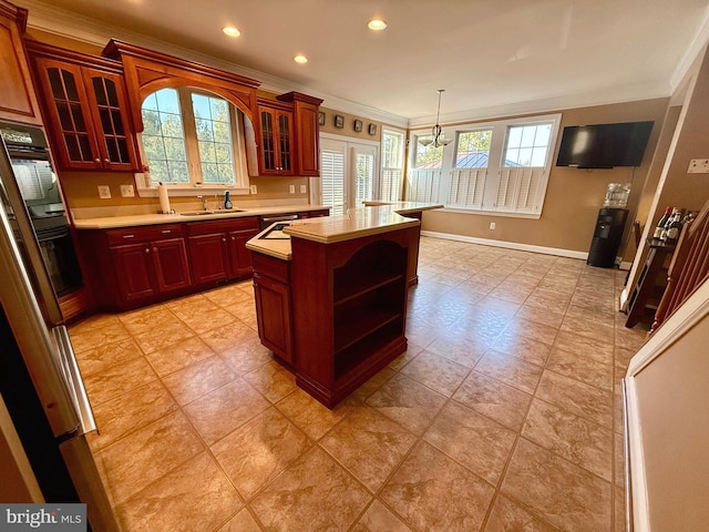 kitchen with crown molding, a healthy amount of sunlight, sink, and a kitchen island