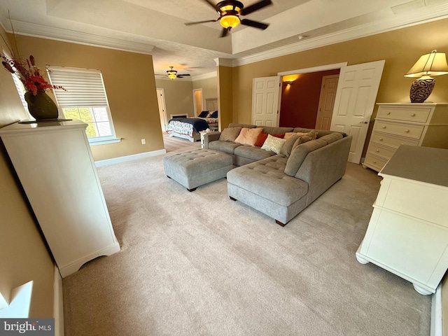 carpeted living room with ornamental molding, a tray ceiling, and ceiling fan