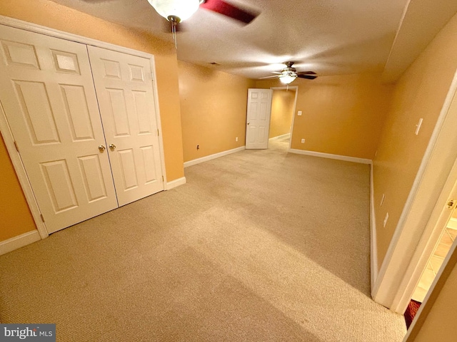 unfurnished bedroom featuring a textured ceiling, carpet flooring, a closet, and ceiling fan