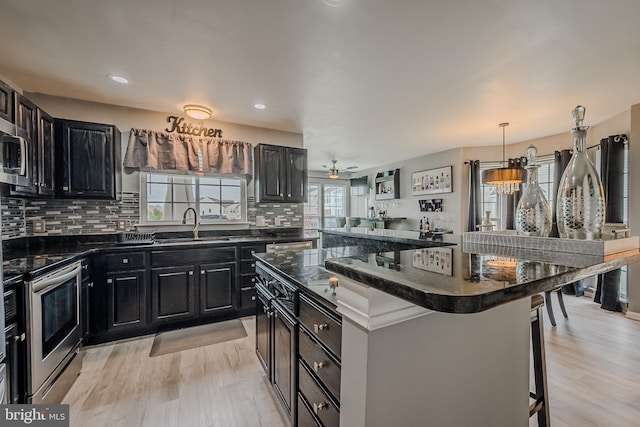 kitchen featuring light hardwood / wood-style flooring, stainless steel appliances, a center island, and a breakfast bar