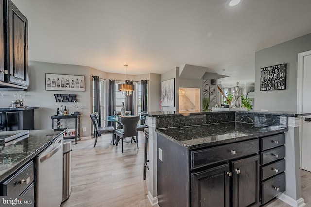 kitchen featuring hanging light fixtures, a kitchen island, light hardwood / wood-style flooring, dishwasher, and dark stone countertops