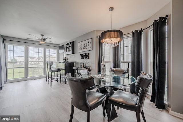 dining area with ceiling fan with notable chandelier and light hardwood / wood-style flooring