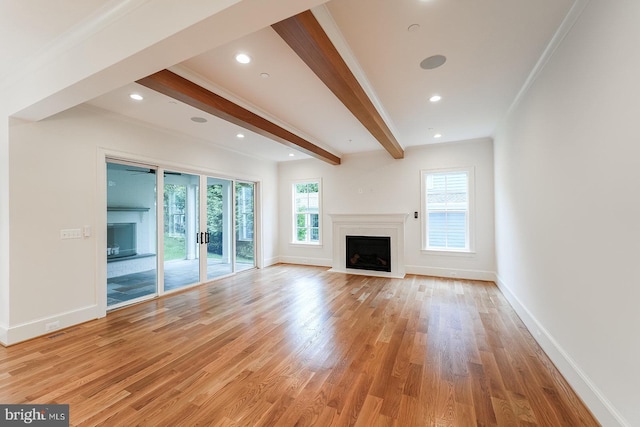 unfurnished living room with beam ceiling, ornamental molding, and light hardwood / wood-style flooring