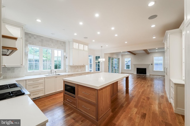 kitchen with wood-type flooring, decorative light fixtures, white cabinetry, and a center island