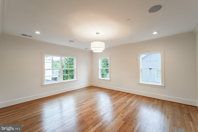 spare room featuring light wood-type flooring and crown molding