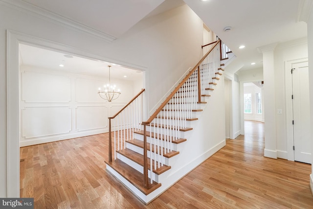 stairway featuring an inviting chandelier, hardwood / wood-style flooring, and ornamental molding