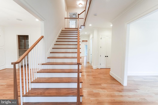 stairway with wood-type flooring and ornamental molding