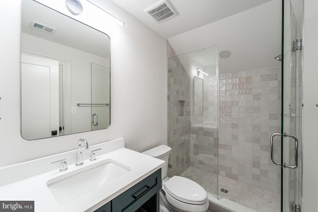 bathroom featuring a shower with shower door, vanity, and toilet