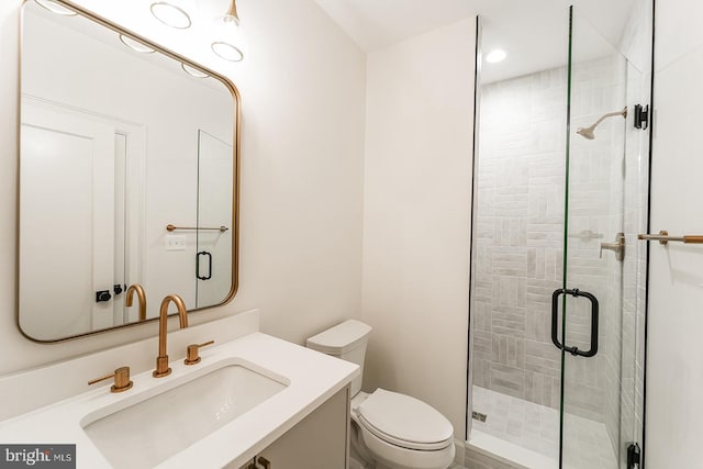 bathroom featuring a shower with door, toilet, and vanity