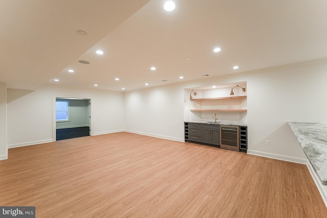 unfurnished living room featuring wine cooler, light wood-type flooring, and sink