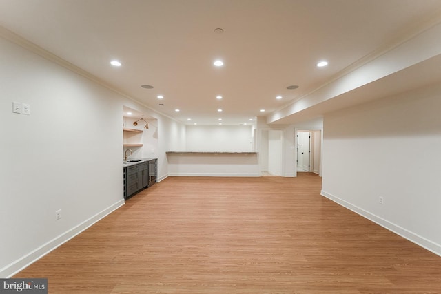 unfurnished living room with ornamental molding, built in features, light hardwood / wood-style floors, and sink