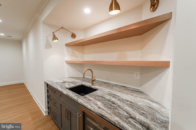 kitchen with light hardwood / wood-style flooring, light stone counters, dark brown cabinetry, and sink