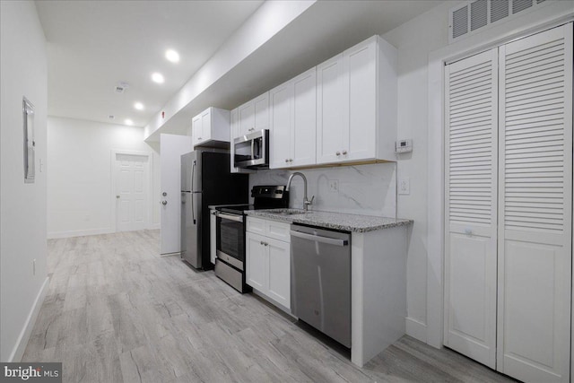 kitchen featuring white cabinets, sink, tasteful backsplash, stainless steel appliances, and light hardwood / wood-style floors