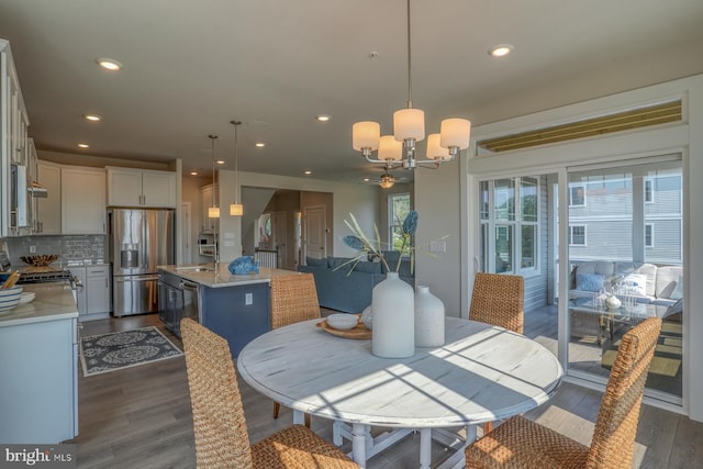 dining room with dark wood-type flooring, an inviting chandelier, and sink