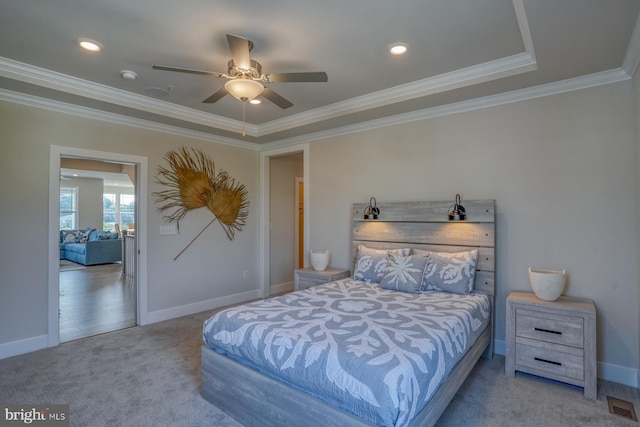 carpeted bedroom featuring ceiling fan, ornamental molding, and a tray ceiling