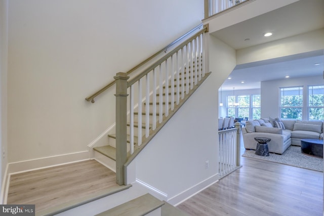 stairs with hardwood / wood-style floors and a notable chandelier