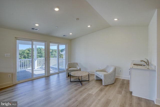 living area featuring light hardwood / wood-style floors, sink, and vaulted ceiling