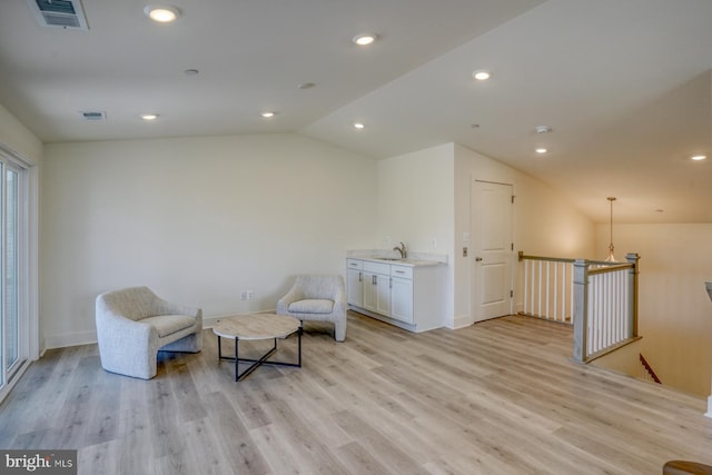 sitting room featuring light hardwood / wood-style floors, lofted ceiling, and sink