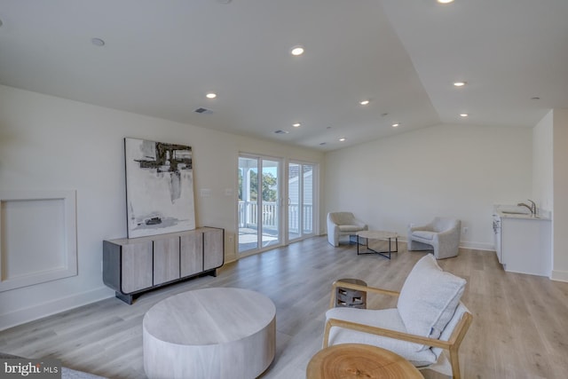 sitting room with sink, vaulted ceiling, and light hardwood / wood-style flooring