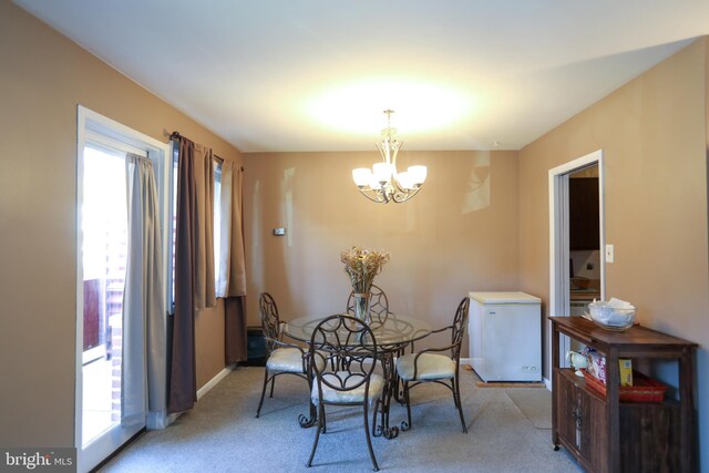 dining area featuring baseboards, light carpet, and a notable chandelier