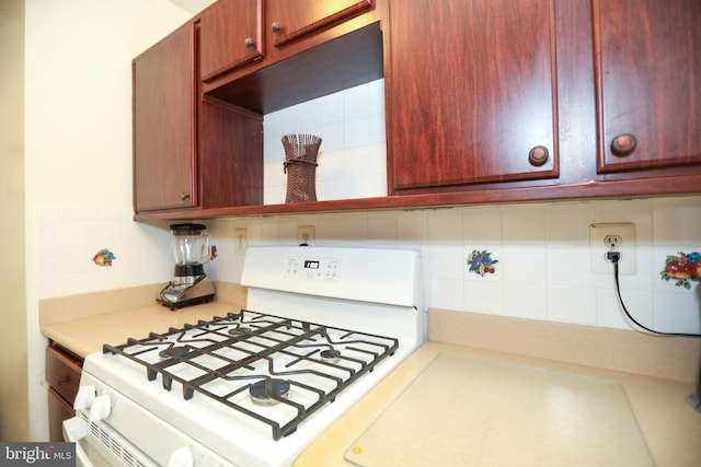 kitchen with white range with gas stovetop, light countertops, and decorative backsplash