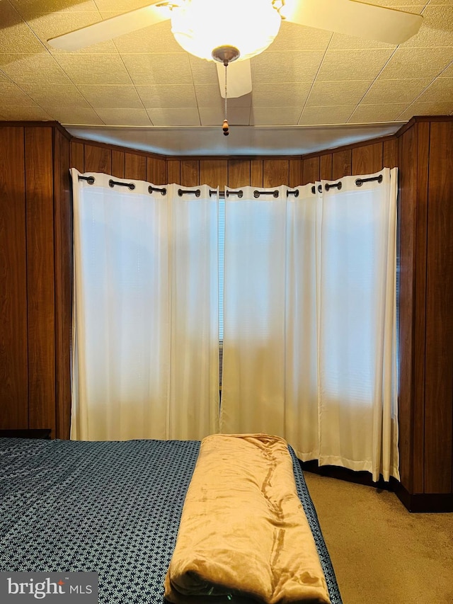 carpeted bedroom featuring wooden walls