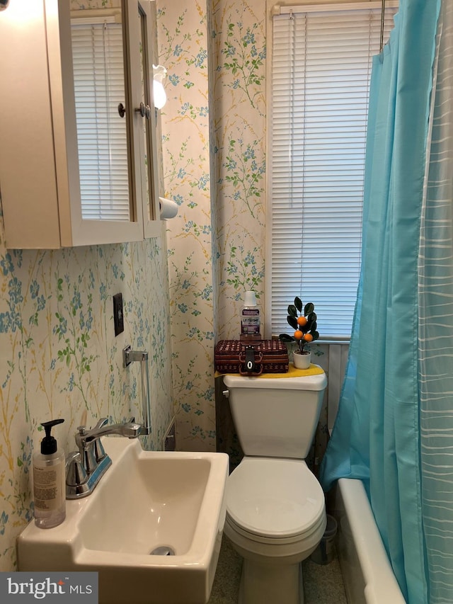 full bathroom featuring toilet, shower / tub combo with curtain, and sink