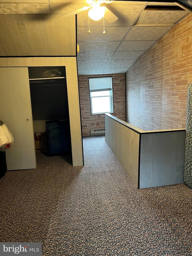 interior space featuring carpet flooring, a baseboard radiator, and brick wall