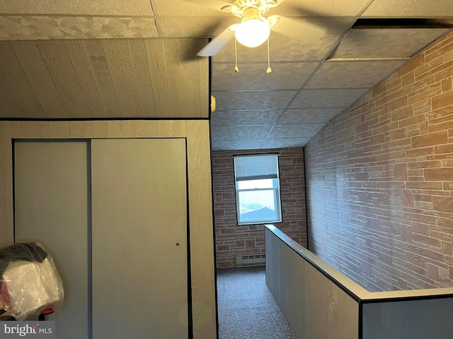 hallway featuring wooden walls, carpet floors, brick wall, and vaulted ceiling