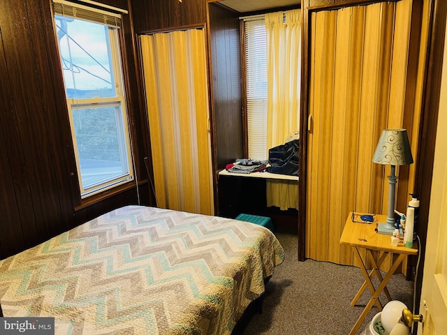 carpeted bedroom featuring wood walls