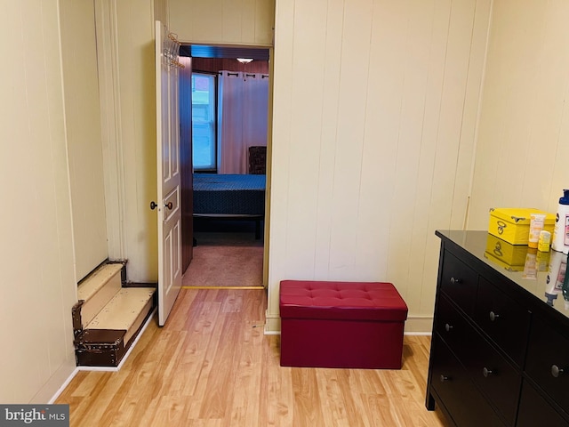 hallway featuring light hardwood / wood-style floors and wooden walls